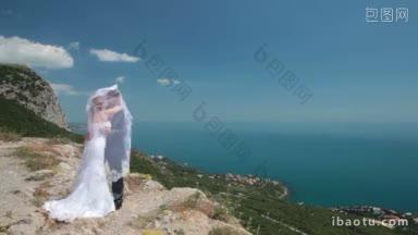 新娘和<strong>新郎</strong>站在峭壁上，背对着蓝天和大海